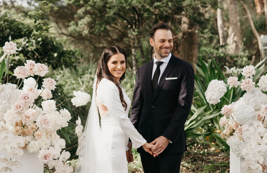Couple holding hands among white garden flowers